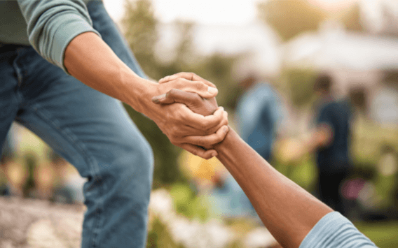 Hands clasped in a community volunteering and outreach moment